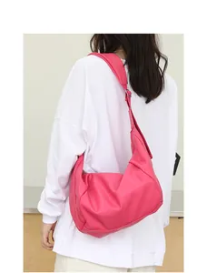 Vista detallada de un bolso bandolera de cuero PU plisado rosa fucsia en una modelo.
