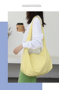 Model carrying a pale yellow nylon crescent shoulder bag in a minimalist indoor setting