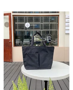 Detailansicht einer schwarzen Canvas-Tragetasche mit zwei Fronttaschen auf weißem Tisch