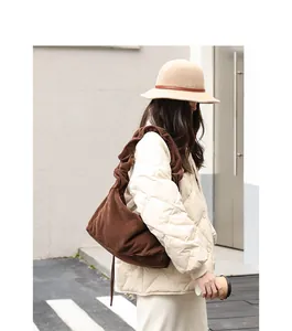 Brown corduroy shoulder bag for women styled with a beige quilted jacket and winter hat