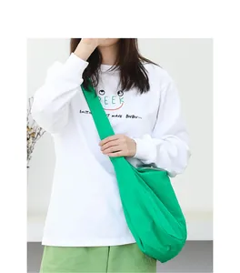 Detailed shot of a vibrant green nylon crossbody bag styled with casual white top