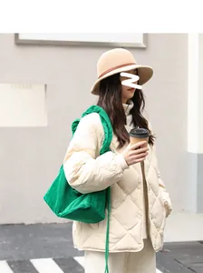 Detail shot of a vibrant green corduroy drawstring shoulder bag worn by a model