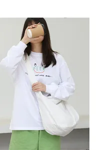 Detail view of a large white nylon crossbody bag worn by a model in casual style