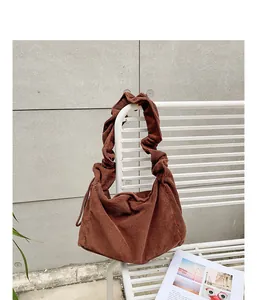 Close-up of brown retro corduroy shoulder bag with scrunchie strap on white bench