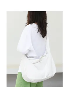 Back view detail of a minimalist white nylon shoulder bag worn by a female model.