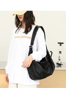 Detalle de un bolso hobo negro minimalista con textura de cuero suave y pliegues.