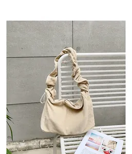Beige corduroy shoulder bag with an elegant ruffled strap shown on a white bench