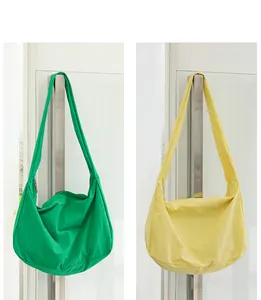Close-up of green and yellow minimalist nylon crossbody bags hanging on a handle