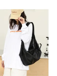 Vista detallada de un bolso hobo de cuero PU plisado negro llevado al hombro por modelo.
