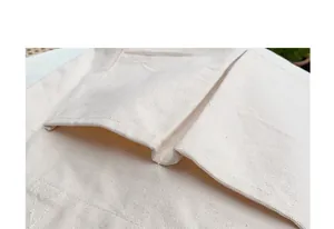 Detailansicht der robusten Nähte und Tasche einer cremefarbenen Canvas-Tragetasche.
