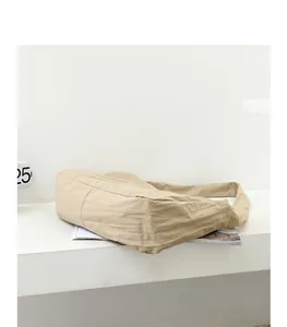 Side view detail of a minimalist beige nylon crossbody bag on a white shelf display.