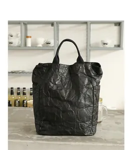 Detailed view of a black DuPont paper tote bag with vintage crinkle texture in a cafe setting