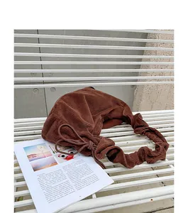 Detailed view of a retro brown corduroy drawstring shoulder bag on a white bench.
