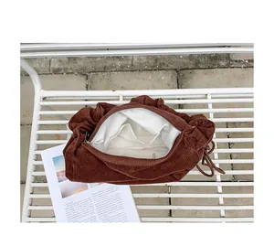 Interior detail of brown corduroy shoulder bag showing white lining and pockets
