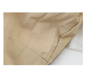 Close-up detail of beige nylon fabric and fine stitching on a shoulder bag