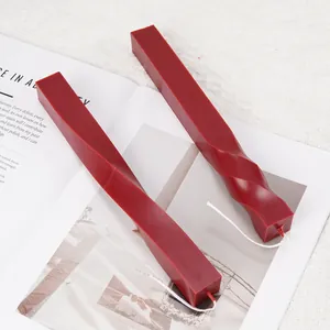 Detail of two dark red twisted spiral square column scented candles