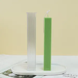Detalle del molde de acrílico para velas y vela de pilar verde texturizada.