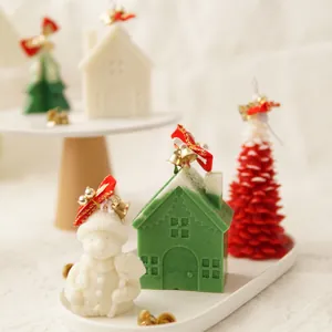 Festive handmade Christmas candles in snowman, house and tree shapes with bell decorations