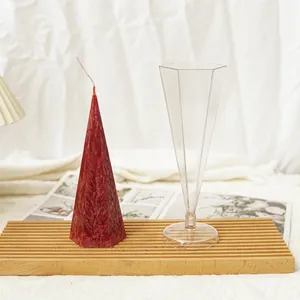 Hexagonal pyramid candle mold with finished red wax candle on wooden board