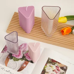 Detailed view of triangular ribbed candle molds and finished wax creations on a wooden tray