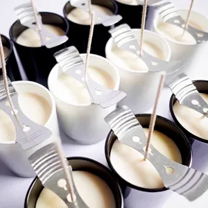 Macro detail of metal three-hole candle wick centering holders on handmade soy wax candles