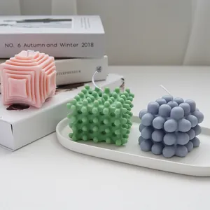 Close-up of decorative geometric scented candles in pink, green, and blue on a tray