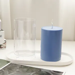 Detail of clear plastic cylindrical DIY candle mold next to a finished blue wax candle.