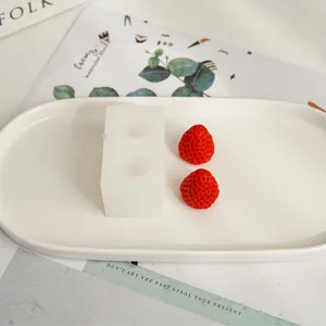 Realistic strawberry silicone mold with finished red wax strawberries on a white tray
