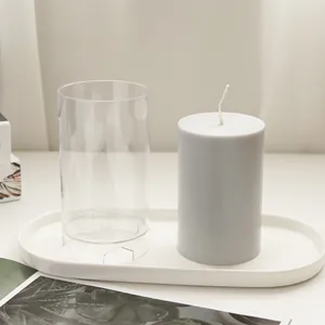Detail of transparent cylindrical candle mold with finished grey wax candle