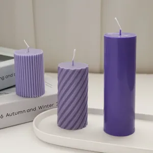 Detailed macro view of purple ribbed, spiral, and smooth pillar candles on a tray