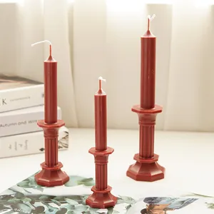 Trio of terracotta pillar candles in octagonal candlestick shapes on a minimal table