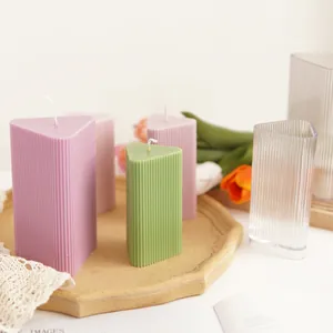 Macro detail of a triangular ribbed geometric candle next to its transparent acrylic mold