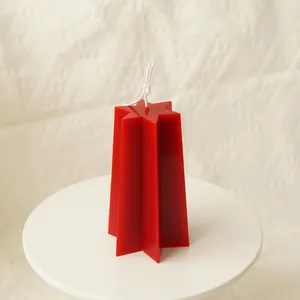 Detail shot of a minimalist red star shaped pillar candle on a white display pedestal