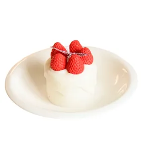 Realistic handmade strawberry cake scented candle displayed on a white ceramic plate