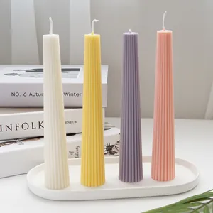 Elegantes Set aus vier konischen, gerippten Stumpenkerzen in Pastellfarben auf einem Tablett
