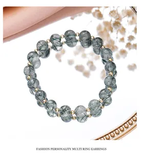 Close-up of green rutilated quartz crystal bracelet with gold beads on a mirror