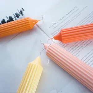 Close-up of orange, pink and yellow ribbed pillar candles on an open English book page