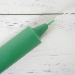Macrodetail van een groene cilindrische kaarsenvorm met een kerkstijl taps toelopende top.