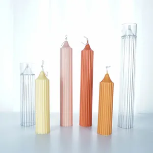 Ribbed pointed candle molds and finished candles in pastel colors on a white surface