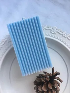 Close-up detail of a light blue rectangular candle with elegant vertical ridges