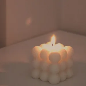 Close-up of a lit white bubble cube scented candle with warm atmospheric lighting