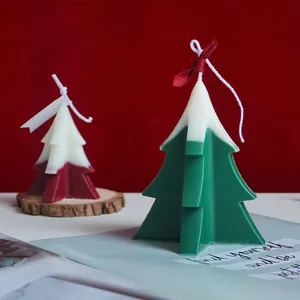 Beautiful close-up of handmade green and red Christmas tree candles with white snow-top effect