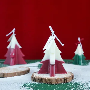 Handmade two-tone Christmas tree scented candles on rustic wooden bases with faux snow