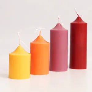 Display of colorful cylindrical church candles with pointed tops in four various heights.
