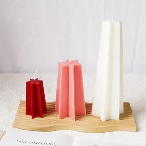 Detail view of finished star-shaped candles in three sizes and colors on a wooden tray.