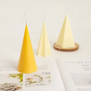 Close-up of yellow cone candle and off-white geometric candles arranged on a magazine