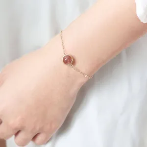 Detailed macro view of an elegant strawberry quartz gemstone bracelet on a wrist