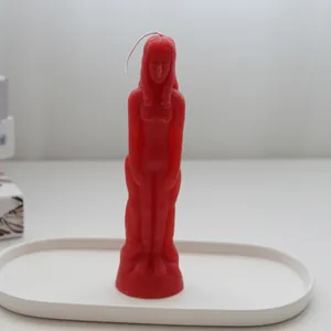 Close-up detail of a red woman-shaped decorative candle on a white oval tray.