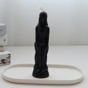 Minimalist black female figure candle standing on a white oval decorative ceramic tray
