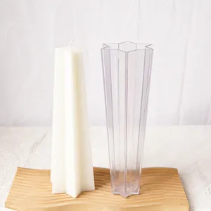 Six-pointed star candle plastic mold with finished white wax candle on wooden tray